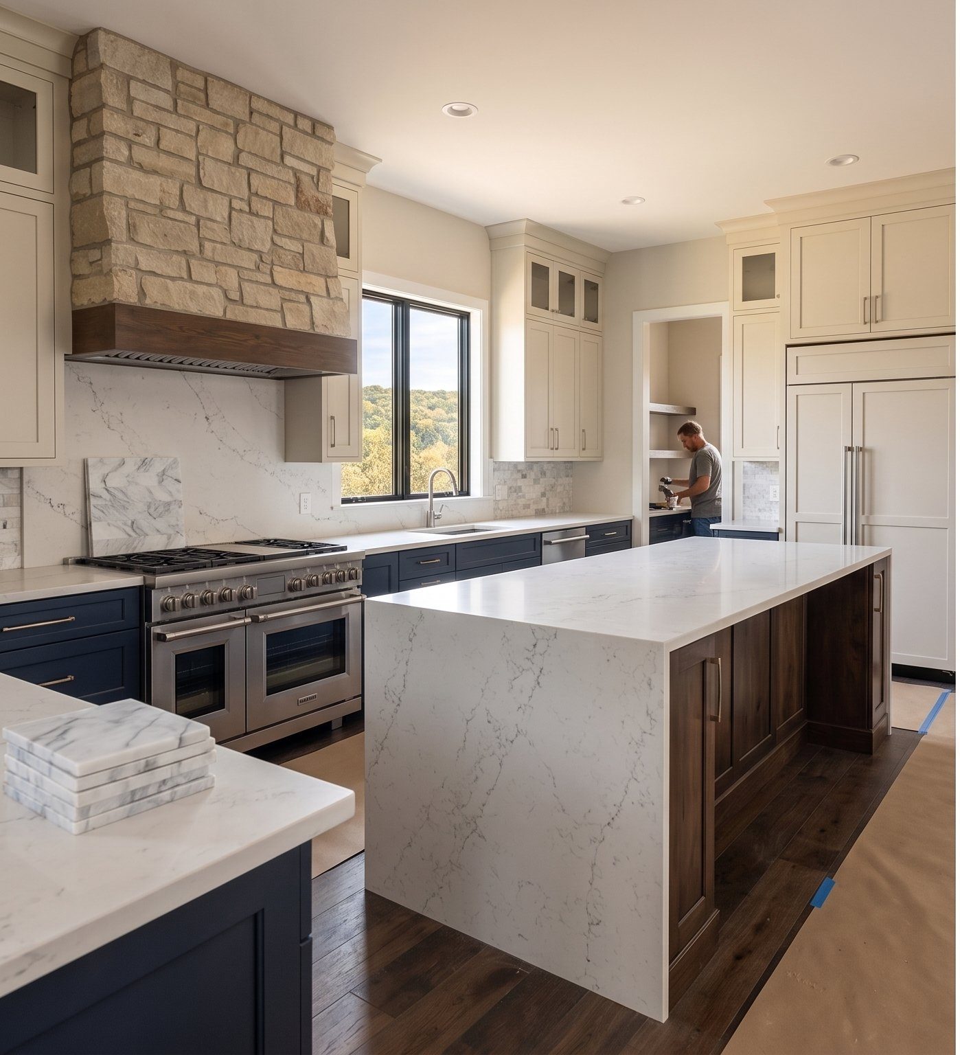 Custom kitchen with navy cabinetry, marble waterfall island, and stone hood vent